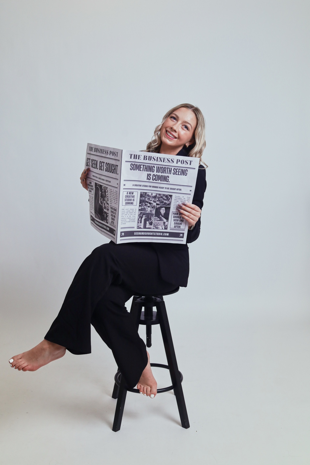 Emma Thompson smiling with the Seen & Sought Studio newspaper